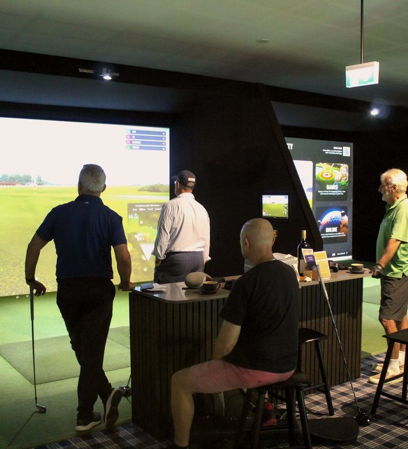 Guests at a TrackMan bay with a high table, watching a shot on the big screen