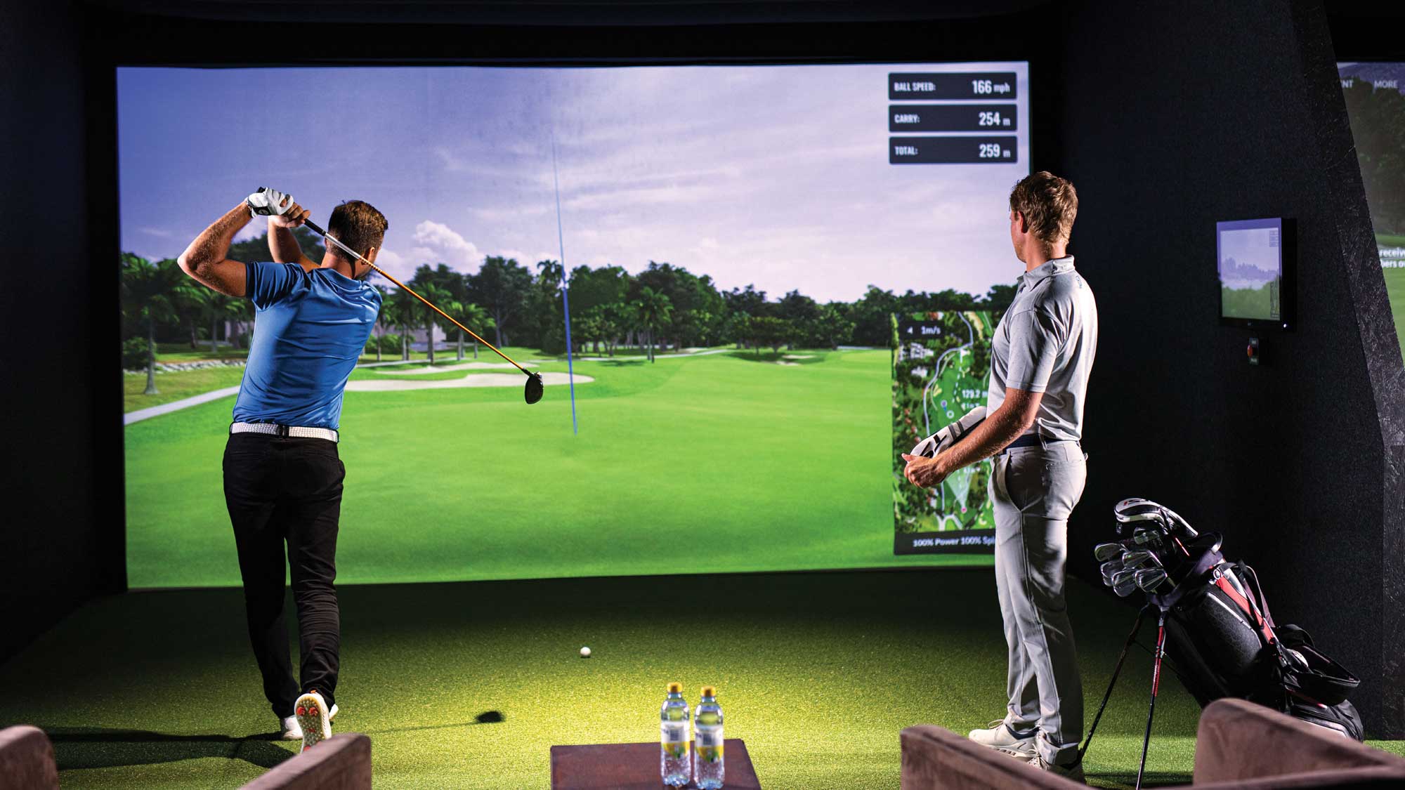 Two male golfers playing indoor golf on a TrackMan golf simulator at Howe2Golf
